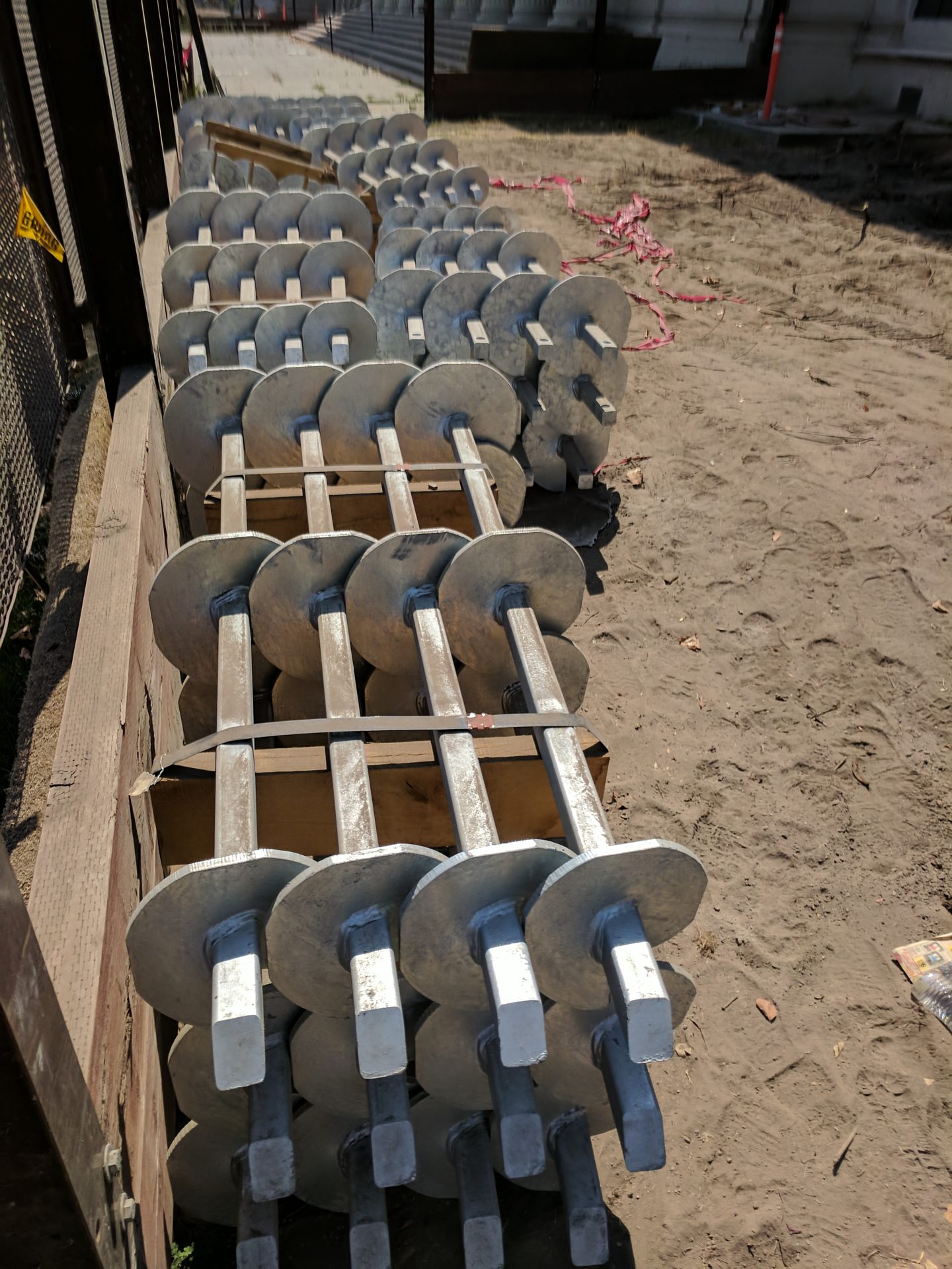A stack of unused helical screw piles on a job site